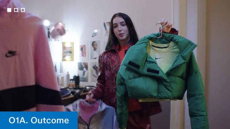Film still labelled 3. Outcome — the chosen green puffer jacket held up to camera